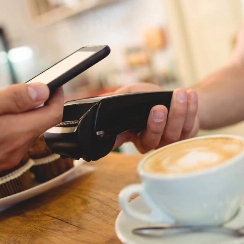 Für eine Tasse Kaffee wird am Bezahlterminal mit dem Handy bezahlt.